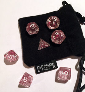 sparkle pink dice, 7 on a white surface and a black bag