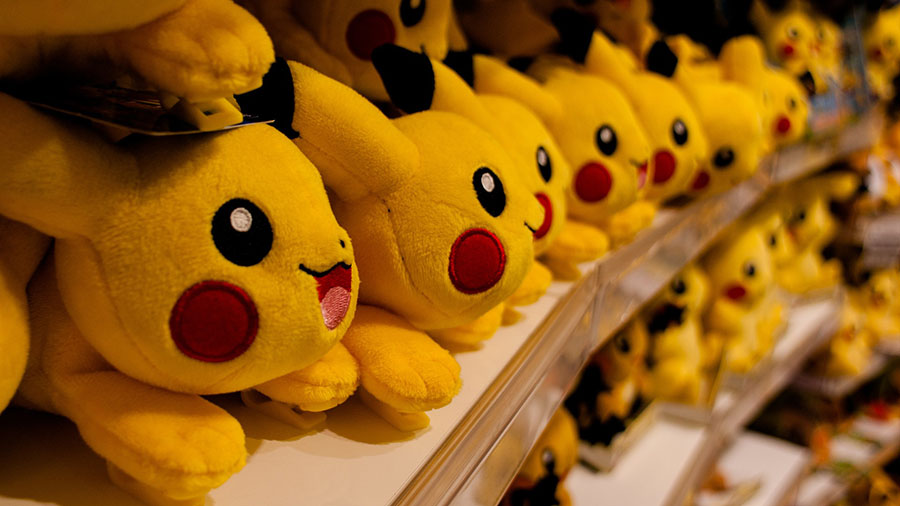 Three shelves filled with plush Pikachu at a store