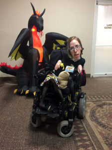 Me in my wheelchair in front of an inflatable dragon. I'm wearing a Batgirl shirt and skirt