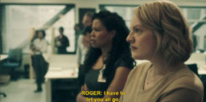 A row of women looking off into the distance at the boss speaking. They are in casual office attire in an office building