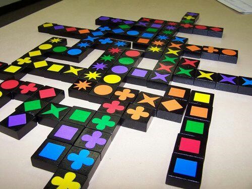 Multicolored square tiles with different colored shapes on them, set up like a Scrabble board