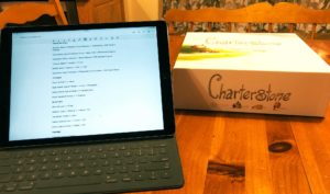 an ipad with a word document on screen. Next to it is a copy of Charterstone