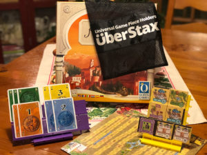 A card game holder, with a stack of two levels, the words UberStax on a black bag behind the components