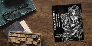 A copy of the zine anthology, with a woman and child on her lap. The book sits on a table