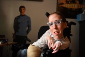 Erin in her wheelchair smiling at the camera
